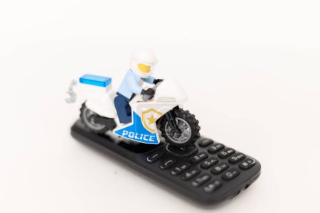 Téléchargez les photos : Policier jouet sur une moto sur un téléphone portable. Protection des données personnelles des utilisateurs. Lutte contre la cybercriminalité - en image libre de droit