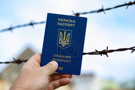 Ukrainian passport against the background of barbed wire. Violation of the law for the departure of citizens of the country