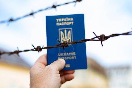 Passeport ukrainien sur fond de fil barbelé. Violation de la loi pour le départ des citoyens du pays