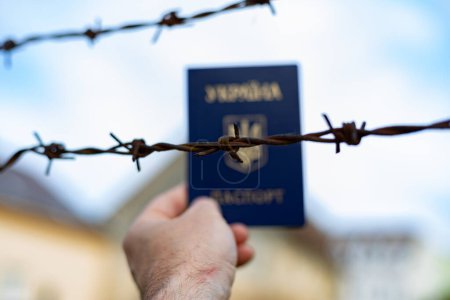 Ukrainischer Pass vor dem Hintergrund von Stacheldraht. Verstoß gegen das Gesetz für die Ausreise von Bürgern des Landes