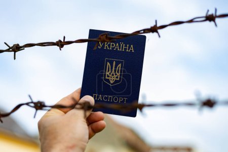 Passeport ukrainien sur fond de fil barbelé. Violation de la loi pour le départ des citoyens du pays