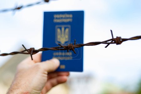 Foto de Pasaporte ucraniano en el contexto de alambre de púas. Violación de la ley de salida de ciudadanos del país - Imagen libre de derechos