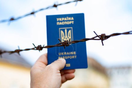 Ukrainian passport against the background of barbed wire. Violation of the law for the departure of citizens of the country