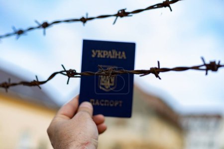 Ukrainischer Pass vor dem Hintergrund von Stacheldraht. Verstoß gegen das Gesetz für die Ausreise von Bürgern des Landes