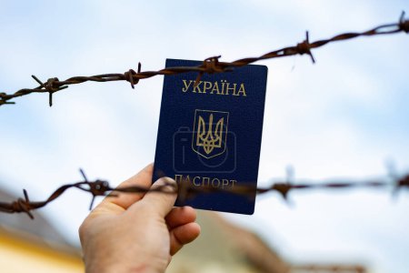 Foto de Pasaporte ucraniano en el contexto de alambre de púas. Violación de la ley de salida de ciudadanos del país - Imagen libre de derechos