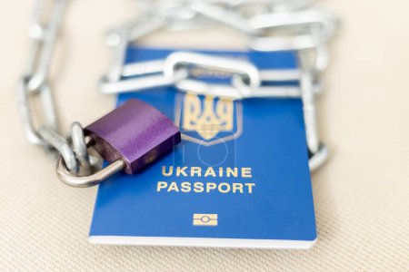 Un cadenas avec une chaîne se trouve sur le passeport. Limitation des droits des réfugiés ukrainiens en Europe