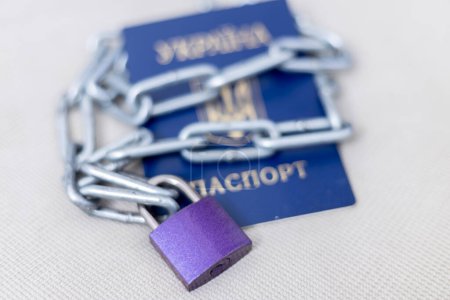 Un cadenas avec une chaîne se trouve sur le passeport. Limitation des droits des réfugiés ukrainiens en Europe