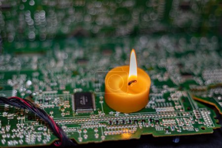 Burning candle on an electronic board. Lack of electricity due to war in Ukraine