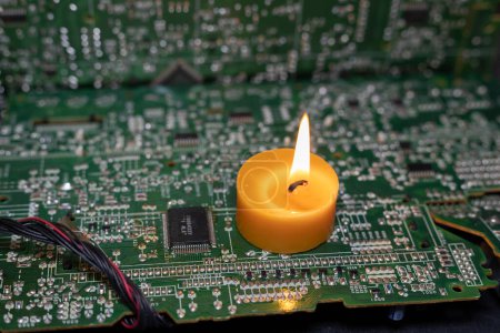 Brennende Kerze auf einer elektronischen Platine. Strommangel durch Krieg in der Ukraine