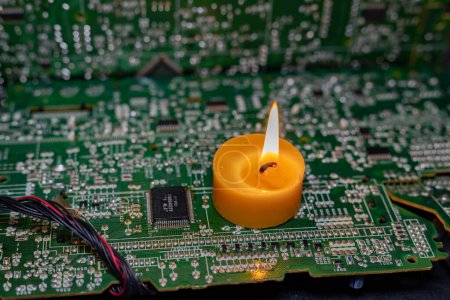 Brennende Kerze auf einer elektronischen Platine. Strommangel durch Krieg in der Ukraine