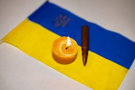 Bougie allumée et balle sur le drapeau ukrainien. Augmentation du nombre de victimes en raison de la poursuite de la guerre en Ukraine