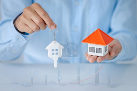 Immobilieninvestoren halten Eigenheimmodelle in der Hand. Sparen Plan zum Kauf von Immobilien, Haus. Persönliches Finanzkonzept für ein Eigenheim. Münzstapel auf Holztisch. Kopierraum. 