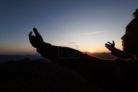 Téléchargez les photos : Silhouette of christian man hand praying,spirituality and religion,man praying to god. Christianity concept.   Freedom and travel adventure. - en image libre de droit