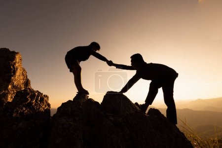 Siluetas de dos personas escalando en la montaña y ayudando. Concepto de ayuda y asistencia. Mano de ayuda, Entrenamiento deportivo.