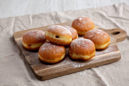 Foto de Polaco de albaricoque casero Paczki Donut con azúcar en polvo en una tabla de madera, vista lateral. - Imagen libre de derechos