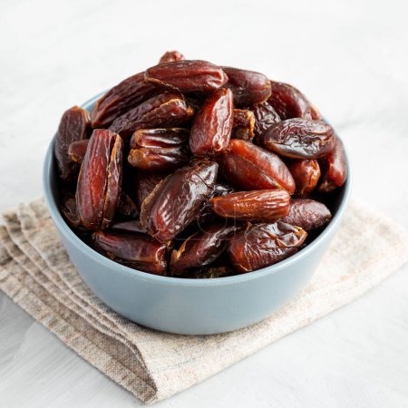 Pitted Organic Dates in Bowl on gray background, low angle view.