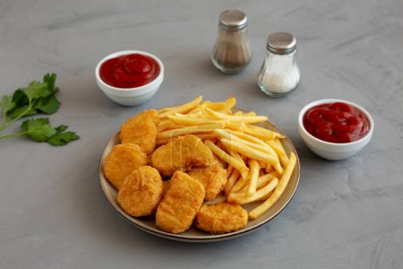 Téléchargez les photos : Pépites de poulet maison et frites avec ketchup sur fond gris, vue latérale. - en image libre de droit