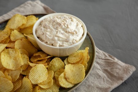 Photo for Crispy Crinkle Potato Chips and French Onion Dip on a Plate, side view. Copy space. - Royalty Free Image