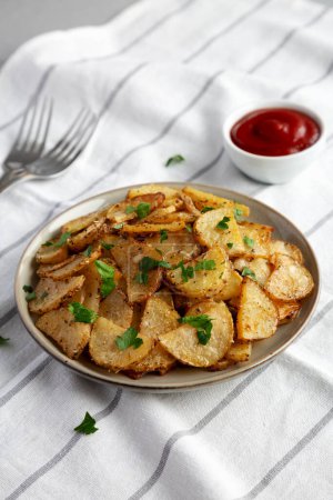Téléchargez les photos : Pommes de terre parmesan à l'ail rôti maison sur une assiette, vue latérale. - en image libre de droit