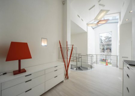 Foto de Moderno interior de hall en casa privada de lujo. Escalera de caracol hecha de vidrio y metal. Cómoda blanca. - Imagen libre de derechos
