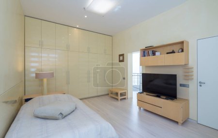 Modern scandic interior in light beige tones of bedroom in luxury apartment. Cozy bed. Huge wardrobe.