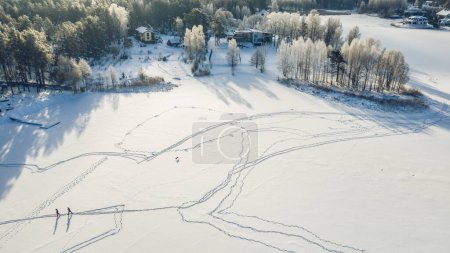 Photo for Top drone view of skiing people on snowy field near cottage village. Winter forest. - Royalty Free Image