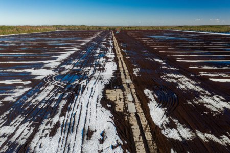 Téléchargez les photos : Vue du drone supérieur du champ sale du début du printemps avec des flaques d'eau et de la glace fondante. Neige et eau sur sol gelé. Journée ensoleillée. - en image libre de droit