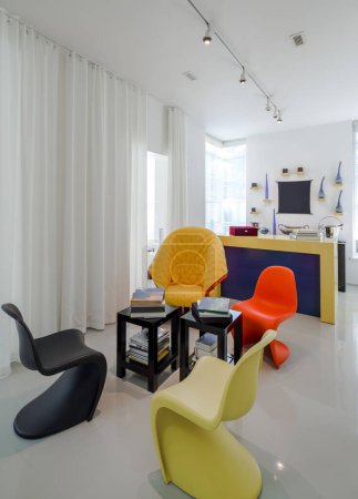 Téléchargez les photos : Intérieur moderne de l'appartement de luxe. Des murs blancs. Chaises noires, jaunes, orange. Livres sur table. - en image libre de droit