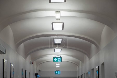 Téléchargez les photos : Plafond blanc dans le couloir avec des panneaux lumineux de sortie. - en image libre de droit