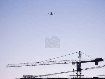 Téléchargez les photos : Grue de construction contre le ciel. Avion volant. Urbain. - en image libre de droit