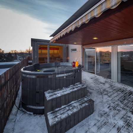 Téléchargez les photos : Terrasse ouverte avec baignoire extérieure en bois chaude en hiver. Maison privée de luxe. Chalet moderne. - en image libre de droit