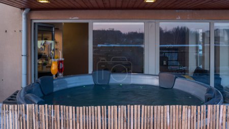 Photo for Open terrace with hot outdoor wooden bath tub at winter. Luxury private house. Modern cottage. Drinks. - Royalty Free Image