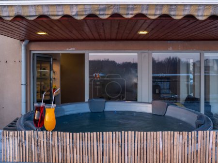 Photo for Open terrace with hot outdoor wooden bath tub at winter. Luxury private house. Modern cottage. Drinks. - Royalty Free Image
