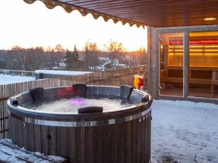 Baignoire extérieure en bois chaude sur la terrasse de la maison privée en hiver. Chalet de luxe. Sauna finlandais.