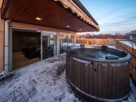 Téléchargez les photos : Terrasse ouverte avec baignoire extérieure en bois chaude en hiver. Maison privée de luxe. Chalet moderne. - en image libre de droit