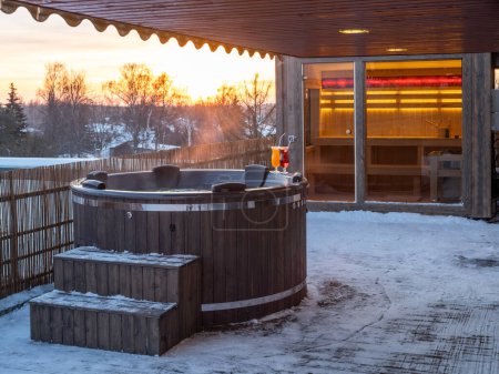 Baignoire extérieure en bois chaude sur la terrasse de la maison privée en hiver. Chalet de luxe. Sauna finlandais.