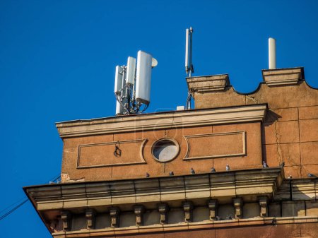 Foto de Antena de comunicación inalámbrica en la azotea del edificio antiguo. Arquitectura moderna. Cielo azul. - Imagen libre de derechos