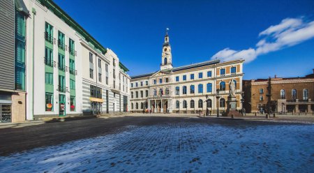 Foto de Plaza del Ayuntamiento de Riga. La torre del reloj. Arquitectura moderna de Letonia. Turismo en Europa. - Imagen libre de derechos