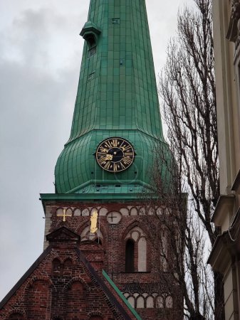Foto de Primer plano de una iglesia católica de ladrillo rojo. El dial está en una aguja verde. - Imagen libre de derechos