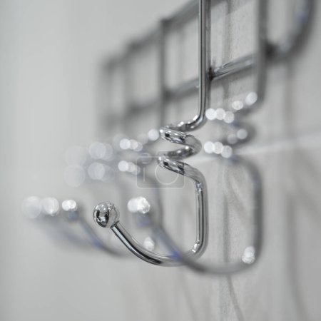 Photo for Metal hanger with many hooks for towels and clothes. Bathroom interior. Close-up. - Royalty Free Image