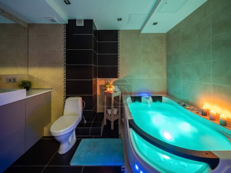 Modernes Interieur des Luxus-Badezimmers in der Wohnung. Beleuchtetes Massagebad mit Wasser. Kerzen. Romantische Atmosphäre.
