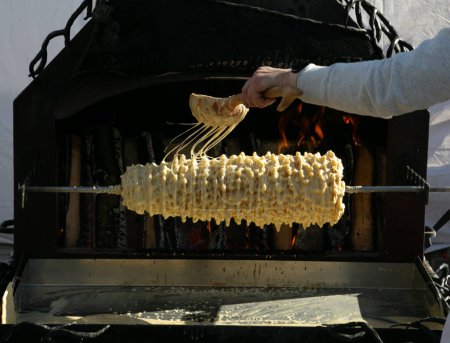 Pastel de tradición Sakotis Baumkuchen horneando en el fuego. Pastel de árbol lituano, Sakotis 
