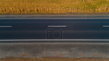 Téléchargez les photos : Drone vue aérienne nouvelle route asphaltée près du champ de blé en été par une journée ensoleillée - en image libre de droit
