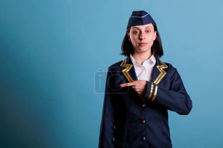 Photo for Flight attendant pointing at side with index finger, aviation academy stewardess advertising product. Air hostess showing in left direction, commercial airlines service promotion - Royalty Free Image