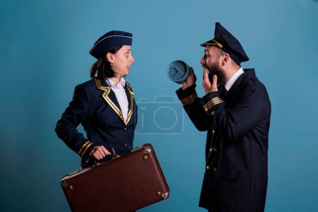 Photo for Stewardess and airplane pilot running late at airport, holding retro alarm clock, carrying baggage. Flight attendant and aircraft captain overslept, looking at time, hurry up at work with luggage - Royalty Free Image