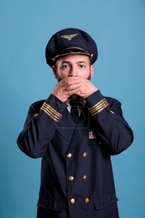 Photo for Airliner captain covering mouth with hands, showing speak no evil gesture, looking at camera. Aviation academy airplane pilot with covered lips front view, censorship, keeping silence concept - Royalty Free Image