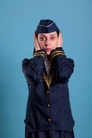 Photo for Flight attendant covering ears with hands, showing hear no evil gesture. Airplane stewardess looking at camera front view, no listen sign, three wise monkeys wisdom concept - Royalty Free Image