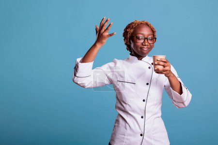 Photo for Kitchen employee enjoying cup of coffee on break. Professional african american cooker savoring freshly brewed coffee. Afro young girl uniformed enjoying taste of coffee. - Royalty Free Image