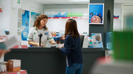 Photo for Multiethnic group of clients paying for medication with credit card, smartwatch and nfc with telephone. People waiting in line to buy pharmaceutical products in pharmacy retail store. Tripod shot. - Royalty Free Image
