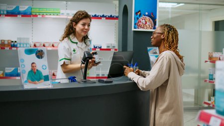 Foto de Mujer afroamericana preguntando a farmacéutico sobre paquetes de pastillas para comprar, tratando de encontrar medicamentos de medicamentos recetados. Cliente femenino que busca productos sanitarios. - Imagen libre de derechos